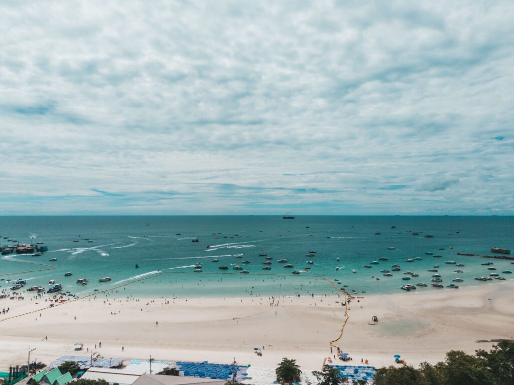 Pattaya Must Visits A stunning aerial view of Pattaya Beach in Chon Buri, Thailand, showcasing blue waters and boats.