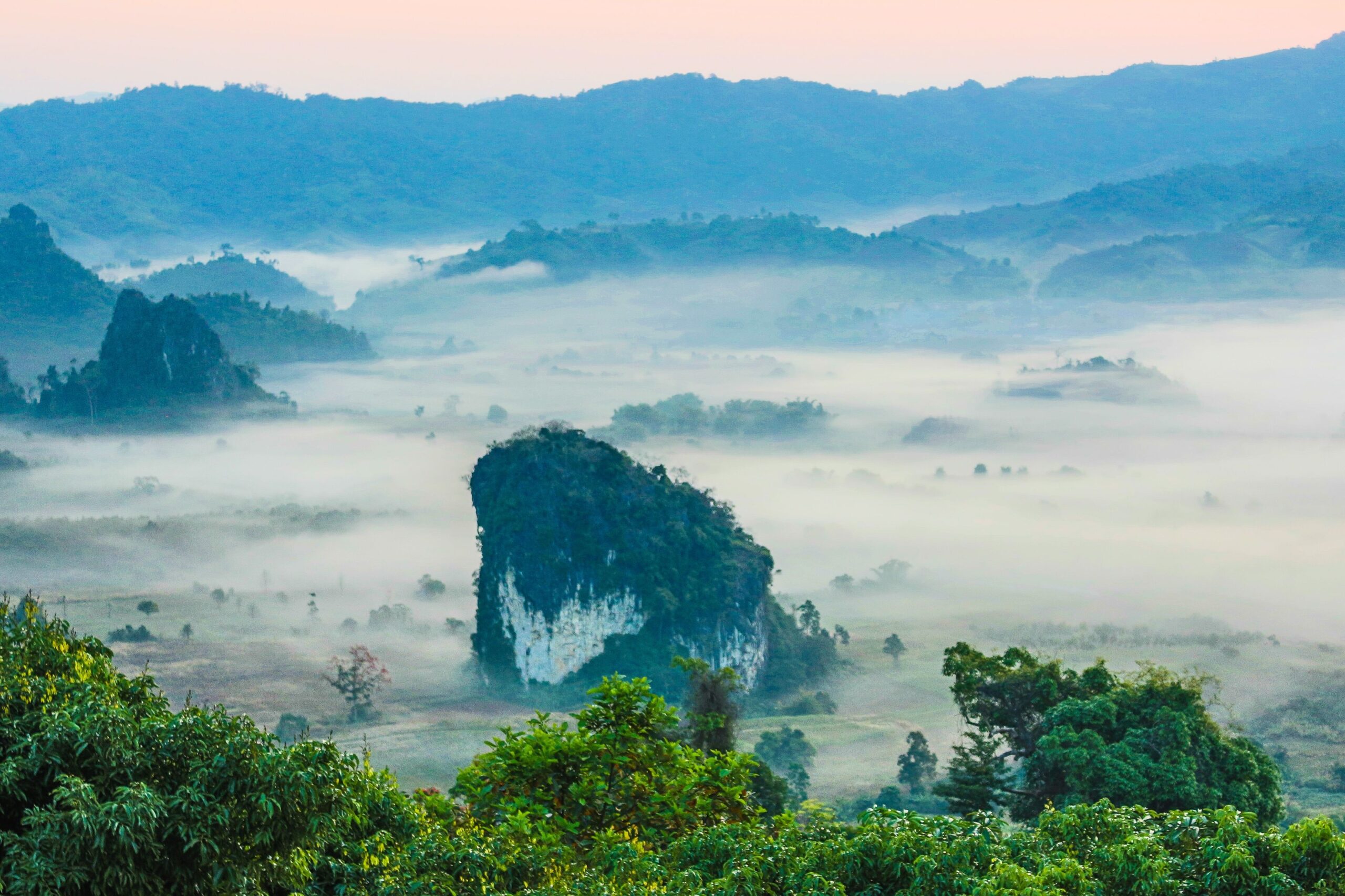 Serene misty landscape with lush greenery and distant mountains in Thailand.