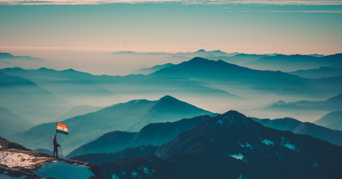 Indian Mountains & Their Hidden Beauty Still Missing Your Visit A breathtaking view of the majestic Himalayas with a person holding an Indian flag, showcasing natural beauty.